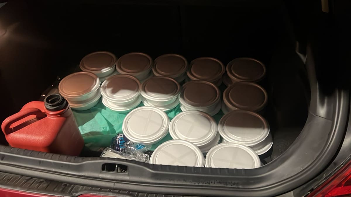 Porta-malas de um carro cheio de marmitas fechadas, prontas para a entrega da noite.