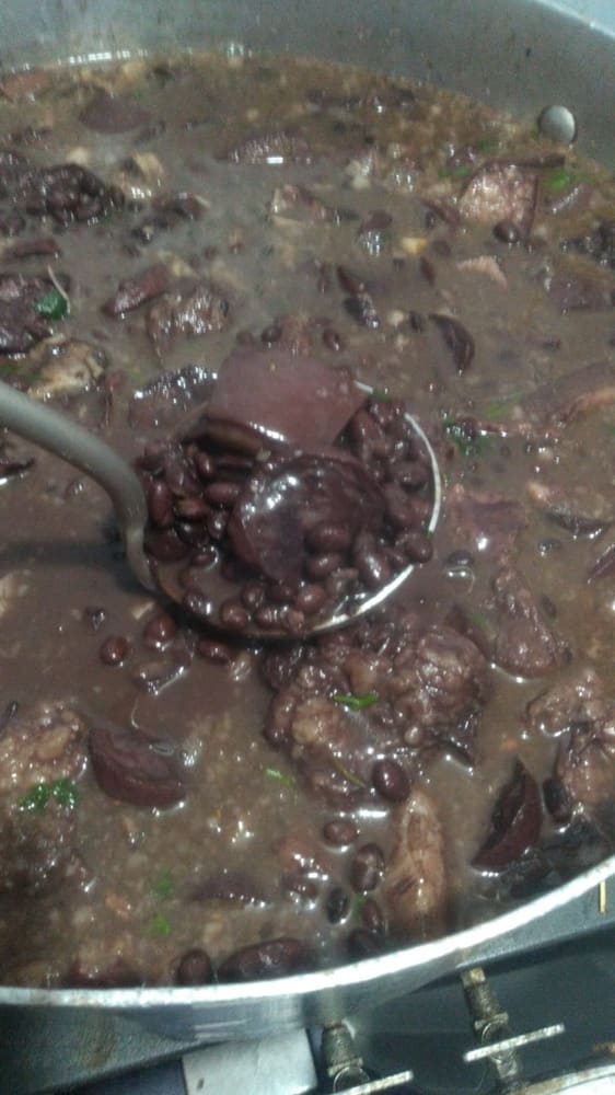 Panelão de feijoada sendo servido com concha grande.