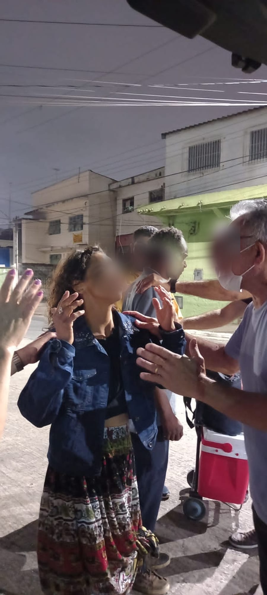 Equipe da Infinito Amor orando com pessoas na rua. Rostos preservados.