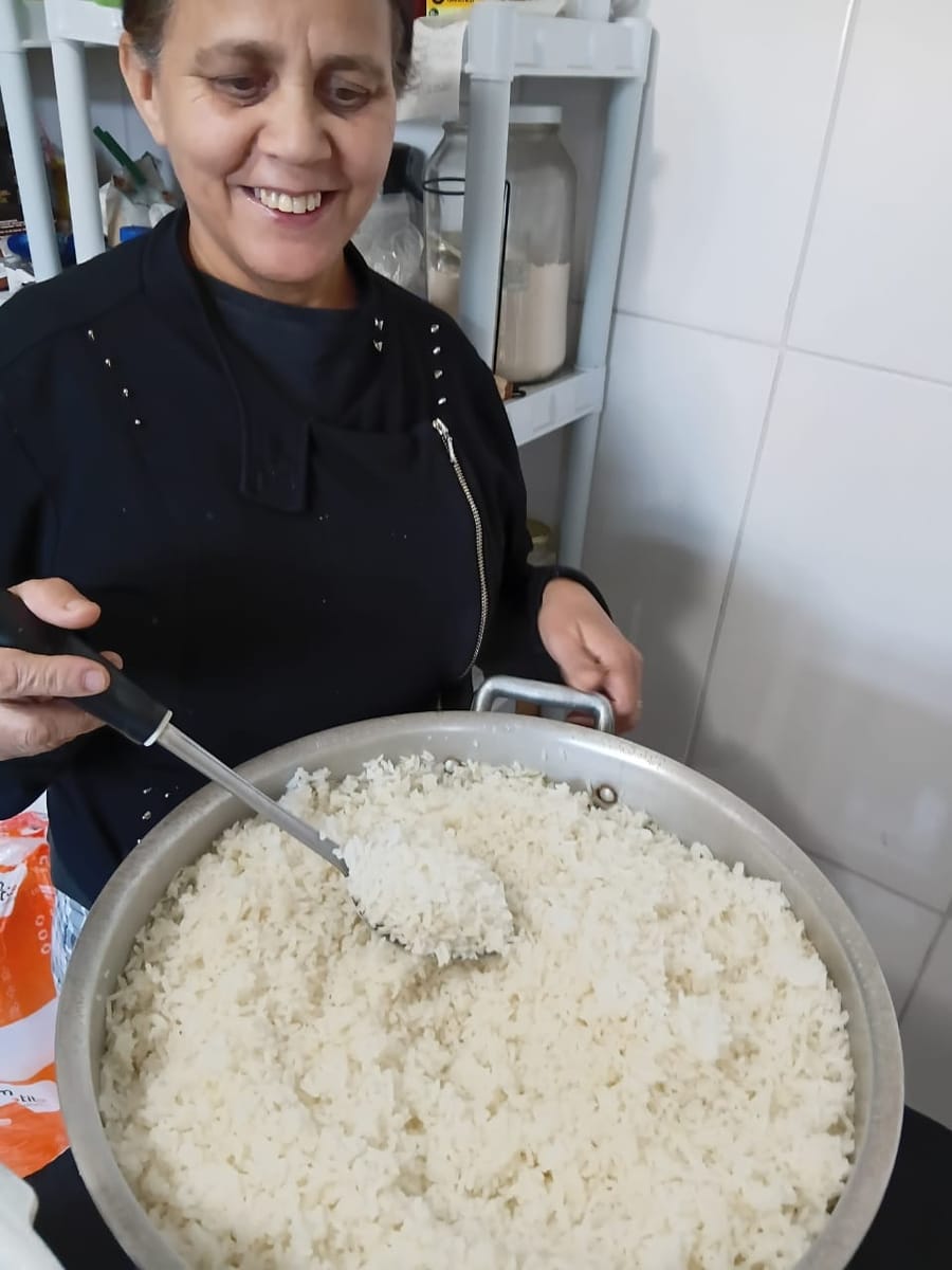 A irmã Dorinha servindo o arroz na cozinha da igreja.