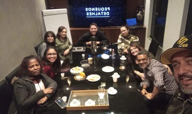 Os voluntários reunidos em volta da mesa, sorrindo para a câmera.
