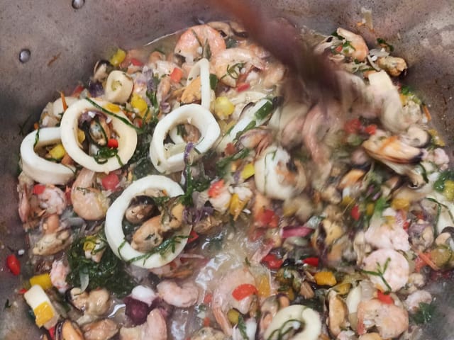 Panelão de paella com camarão, lula e legumes, preparado para a confraternização.